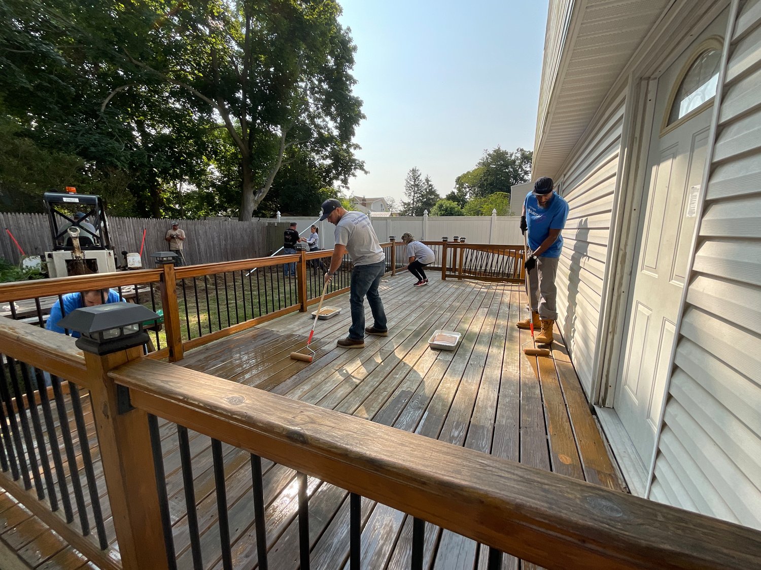 National Grid employees staining the deck and landscaping the yard at a United Veterans Beacon House.